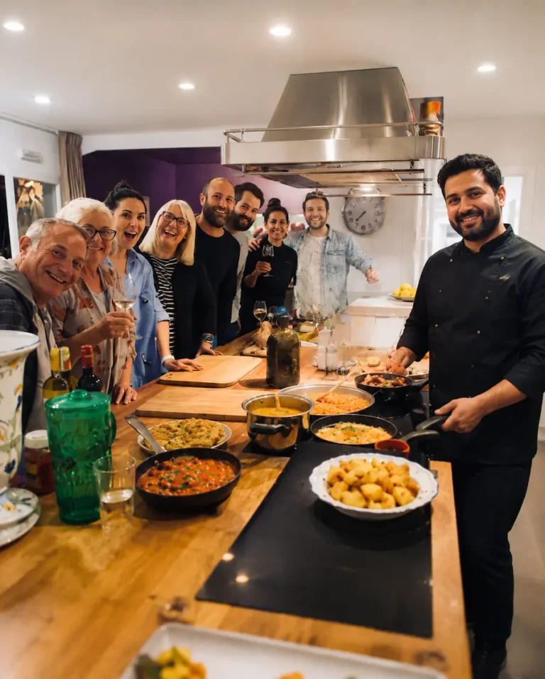 Private chef hosting a group dining experience in a modern kitchen with guests enjoying freshly prepared food.